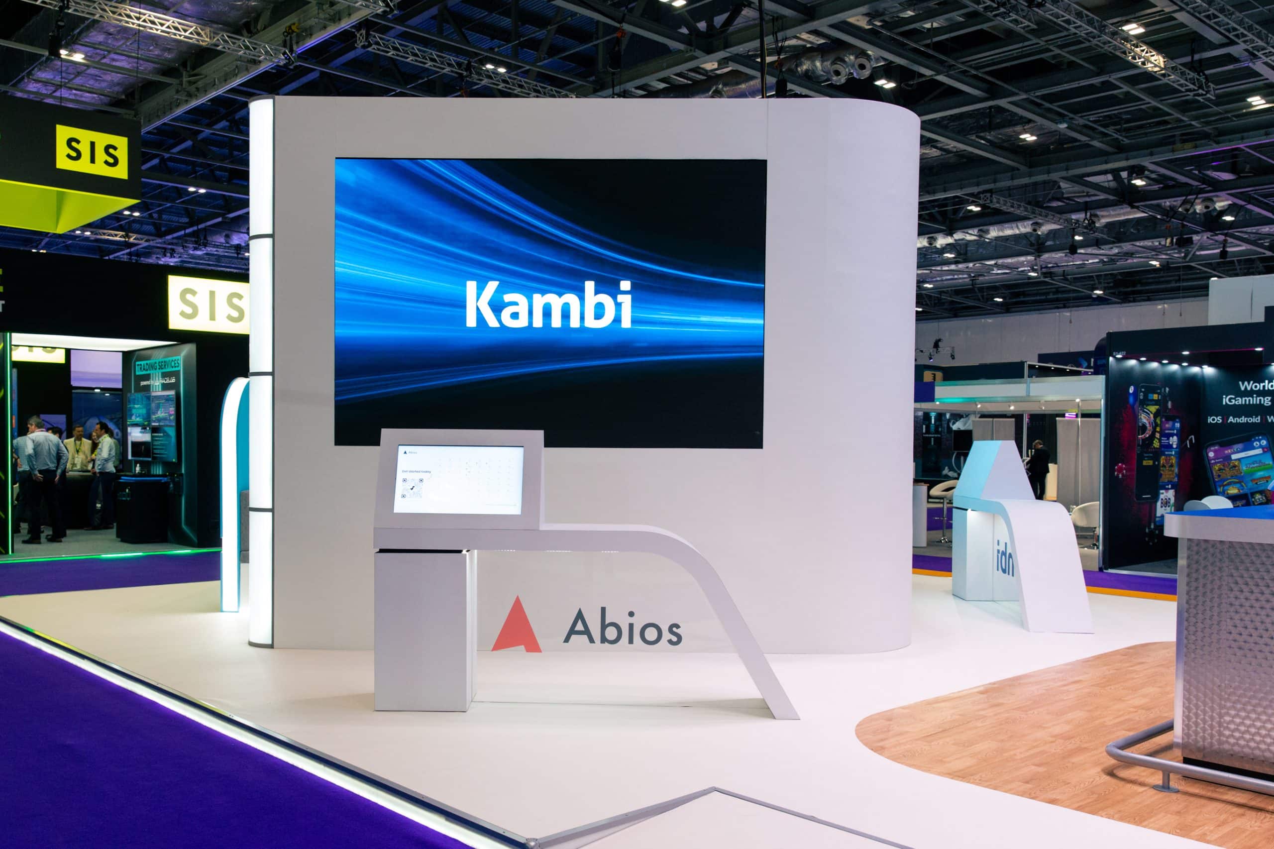 A large display at an event featuring a prominent screen with a sign that reads %22Kambi%22 in bold letters.