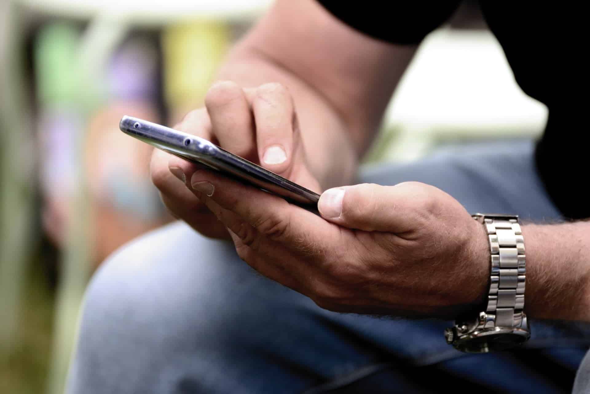 A close up picture of a male holding his phone.