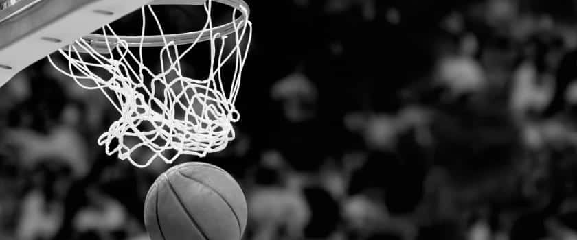 A black and white close up photo of a basketball going through the net.